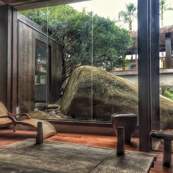 Casa de luxo projetada pela POKT Design+Arquitetura na Ilha do Japão, em Angra dos Reis, construída circundando uma grande rocha natural, com lago de carpas na base e arquitetura temática integrada à paisagem.